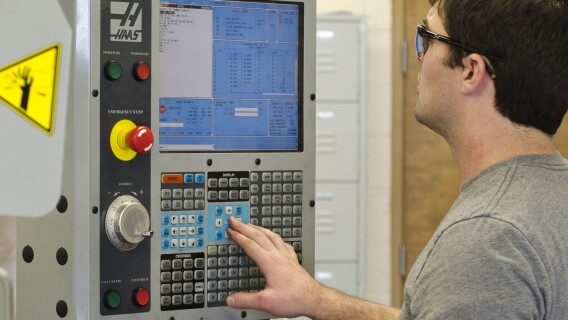 A student works with a Haas electrical cabinet in a Manufacturing Processes Lab.