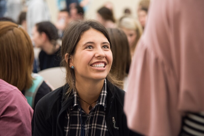 A student sitting down smiling up at another student 