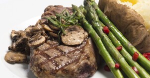 A photo from BYU-Idaho Food Service Catering of a Steak and Asparagus with sautéed mushrooms and a baked potato on the side.